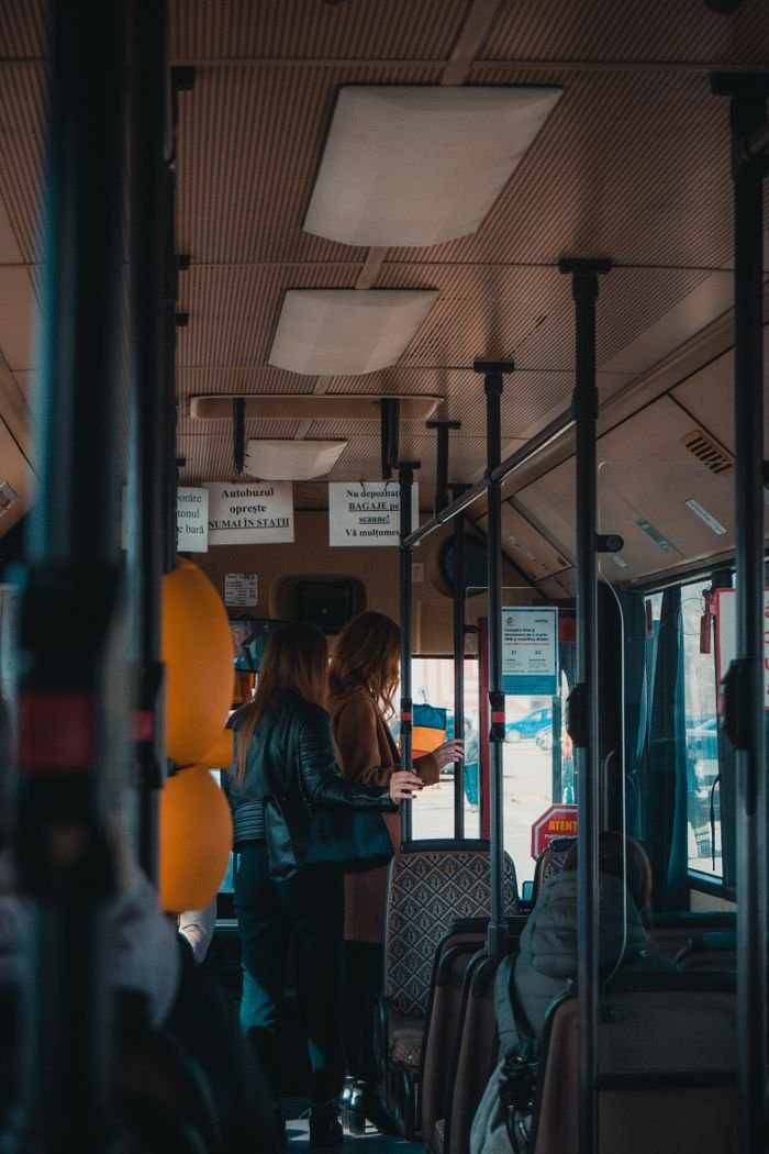 Home Interior shot of women commuting inside a city bus during the day, showcasing urban travel.