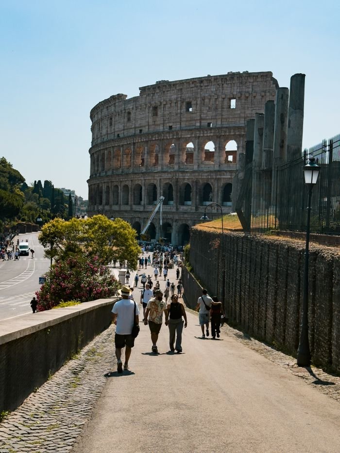 View of the Colosseum in Rome with tourists walking nearby, captured on a sunny day.