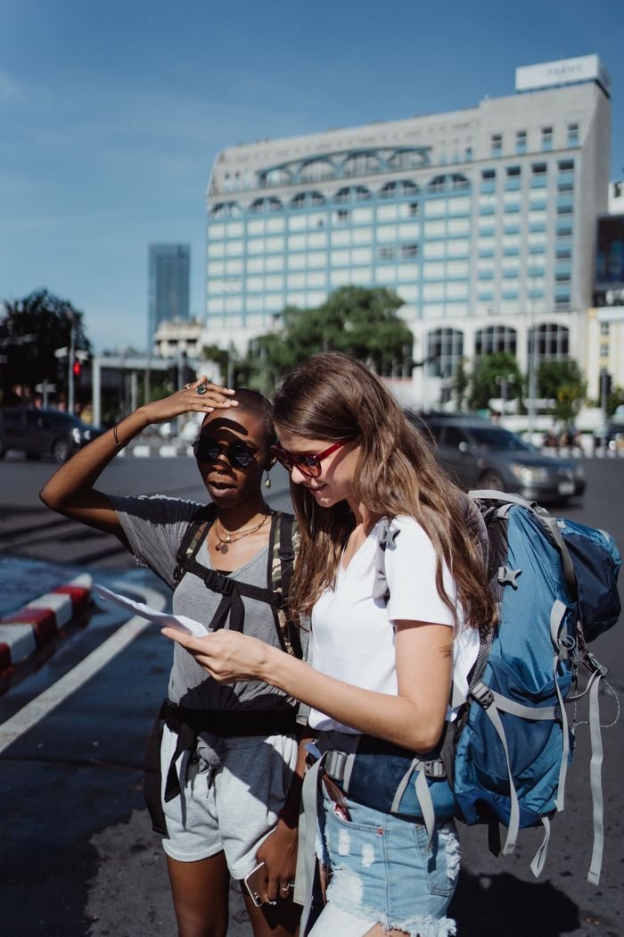 Home Two young women using a map as they explore a city in the summer sun.
