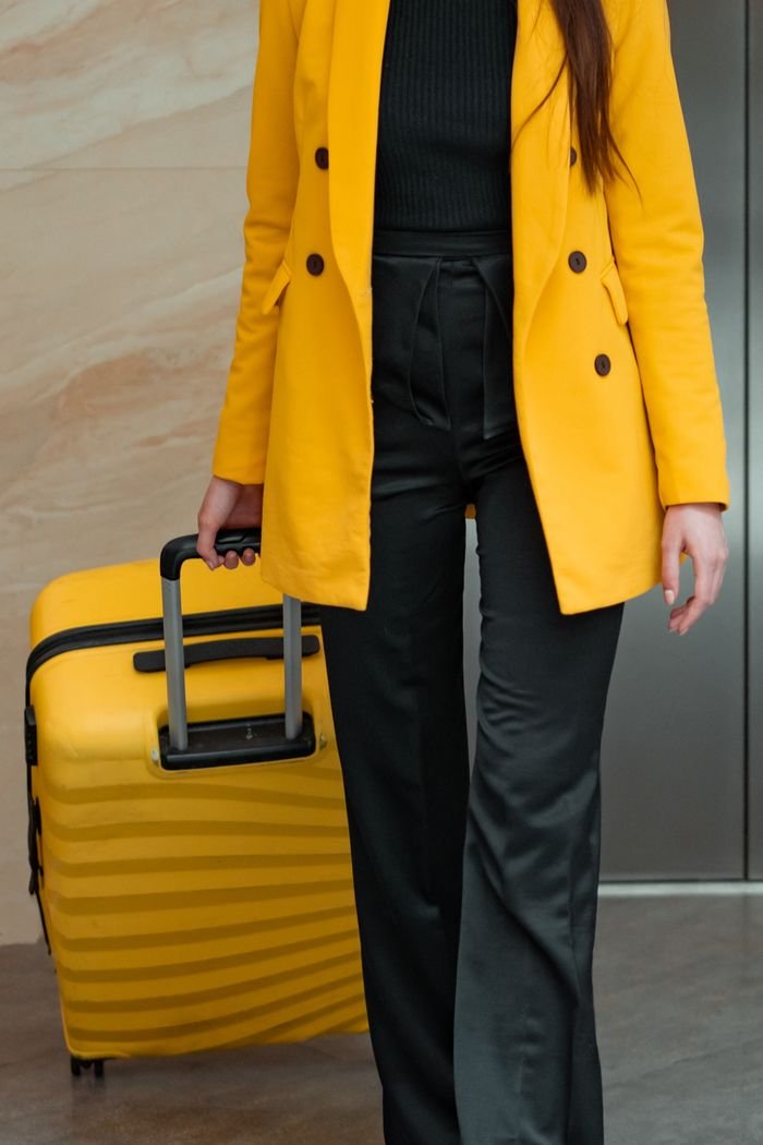 Cookie Policy Woman in yellow coat with rolling luggage, ready for travel. A modern fashion and travel concept.